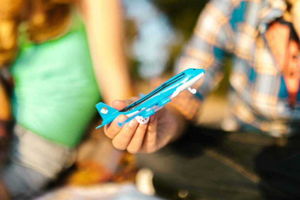 A child's hand holds a blue toy airplane, pretending to make it fly.